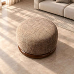 Close-up of Hekolina Brown Round Ottoman, highlighting rounded upholstered body, woven-look texture, and piped top edge.