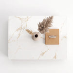Top view of Lumi Solid Surface Gold White Coffee Table with a beige vase holding dried pampas grass and a closed tan notebook with a decorative clip on top.