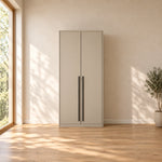 Balomora 2 Door Wooden Wardrobe: long black handles, a neutral outer case and a straight plinth beside a bedroom window.