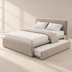 Hensylona Taupe Kids Trundle Bed featuring a plain padded headboard alongside white quilted bedding in a sunlit bedroom.