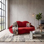 Alternate angle of Kissy Red Velvet Modern 2-Seater Sofa, showing plush cushioning with its construction clearly visible.