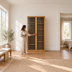 Porteriy 2 Door Wooden Closet Cabinet beside a woman reaching toward the door, featuring two smoke-grey glass doors.