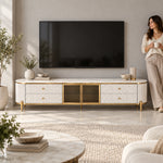 Stillvolra White Marble Top TV Unit beneath a wall-mounted TV with a woman nearby, showing gold-framed glass doors.
