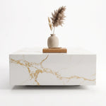 Lumi Solid Surface Gold White Coffee Table with smooth white surface and elegant gold veining, minimalist design topped with a beige vase and decorative pampas grass.
