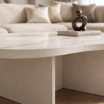 Close-up of a modern, curved white solid surface coffee table with subtle gold veining, styled in a contemporary living room setting with neutral-toned sofa cushions, featuring the Cloud Curve Solid Surface Gold Coffee Table.