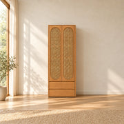 Alvarario 2 Door Wooden Cane Wardrobe with Drawer pairs a natural wood finish with rounded woven inserts in a sunlit bedroom.