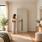 Balomora 2 Door Wooden Wardrobe, two plain beige doors and long black handles, with a woman standing beside the cabinet.