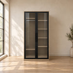 Balomora 2 Door Transparent Glass Cabinet Storage with smoked-glass panels and a neutral outer case in a sunlit bedroom.