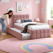 Cemaliso Dusty Pink Kids Trundle Bed, white bedding and dusty pink upholstery, beside a woman making the pull-out bed.
