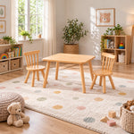 Dukyshola Wooden Kids Table with 2 Chairs pairs splayed round legs with a rounded wood tabletop beside a playroom window.