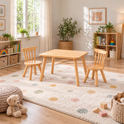 Dukyshola Wooden Kids Table with 2 Chairs pairs splayed round legs with a rounded wood tabletop beside a playroom window.