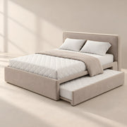 Hensylona Taupe Kids Trundle Bed featuring a plain padded headboard alongside white quilted bedding in a sunlit bedroom.