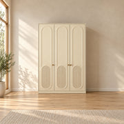 Kapilosa 3 Door Wooden Wardrobe featuring fluted lower panels alongside small brass-tone handles against a bedroom wall.