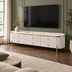 Melsiny White Marble Top TV Unit featuring rounded cream ends alongside six textured drawers beside living room seating.