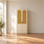 Mossylora Cane Cabinet Storage with Three Drawers, showing woven cane inserts and leaf-shaped pulls in a sunlit bedroom.