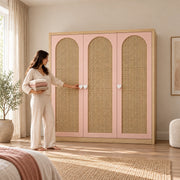 Natupiny 3 Door Rattan Cane Wardrobe beside a woman reaching toward the door; woven door inserts and blush-pink framing.