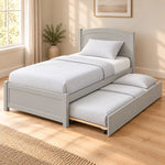 Stompora Grey Kids Trundle Bed featuring an extended side trundle alongside a curved grey headboard in a sunlit bedroom.