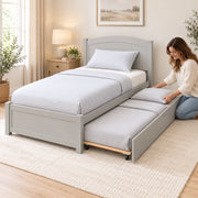 Stompora Grey Kids Trundle Bed, a curved grey headboard and white bedding, with a woman arranging the extended underbed.