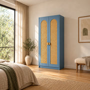 Webinora Blue 2 Door Wooden Cane Wardrobe pairs arched woven panels with a narrow cabinet body beside a bedroom window.