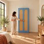 Webinora Blue 2 Door Wooden Cane Wardrobe, two blue doors and tall cane inserts, with a woman standing beside the cabinet.
