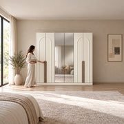 Weltwiyo 6 Door Wooden Wardrobe in a sunlit bedroom, with long wood-tone handles and a woman beside its reflective centre.