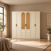Wratinora 6 Door Wooden Wardrobe with Drawers in a furnished bedroom, featuring brass-tone pulls and cream arched doors.