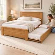 Zikroniya Wooden Kids Trundle Bed beside a woman making the pull-out bed; square wooden posts and projecting top rails.