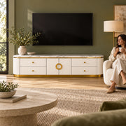 Zondinora White Marble Top TV Unit beneath a wall-mounted TV with a woman nearby, featuring circular gold-tone handles.
