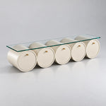 Zoverina Cream Glass Top TV Unit, showing small gold-tone knobs and cream cylindrical sections against a grey backdrop.