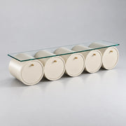 Zoverina Cream Glass Top TV Unit, showing small gold-tone knobs and cream cylindrical sections against a grey backdrop.